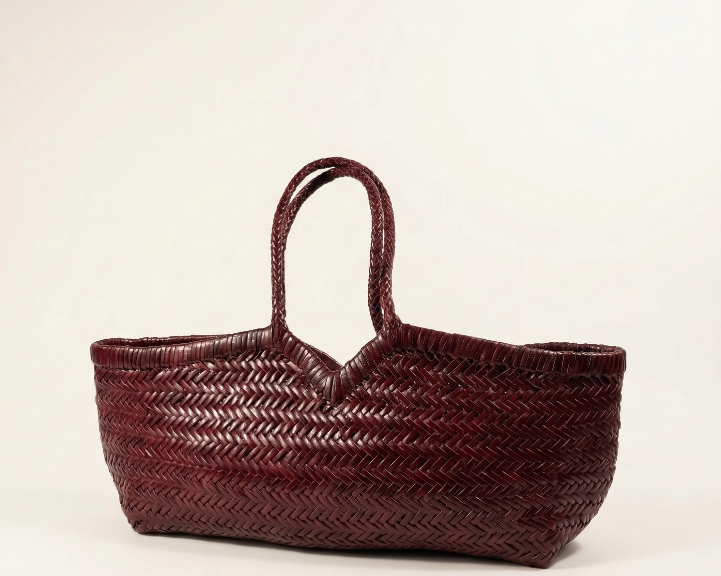 Angled view of the KAPSA woven leather shoulder bag in deep maroon