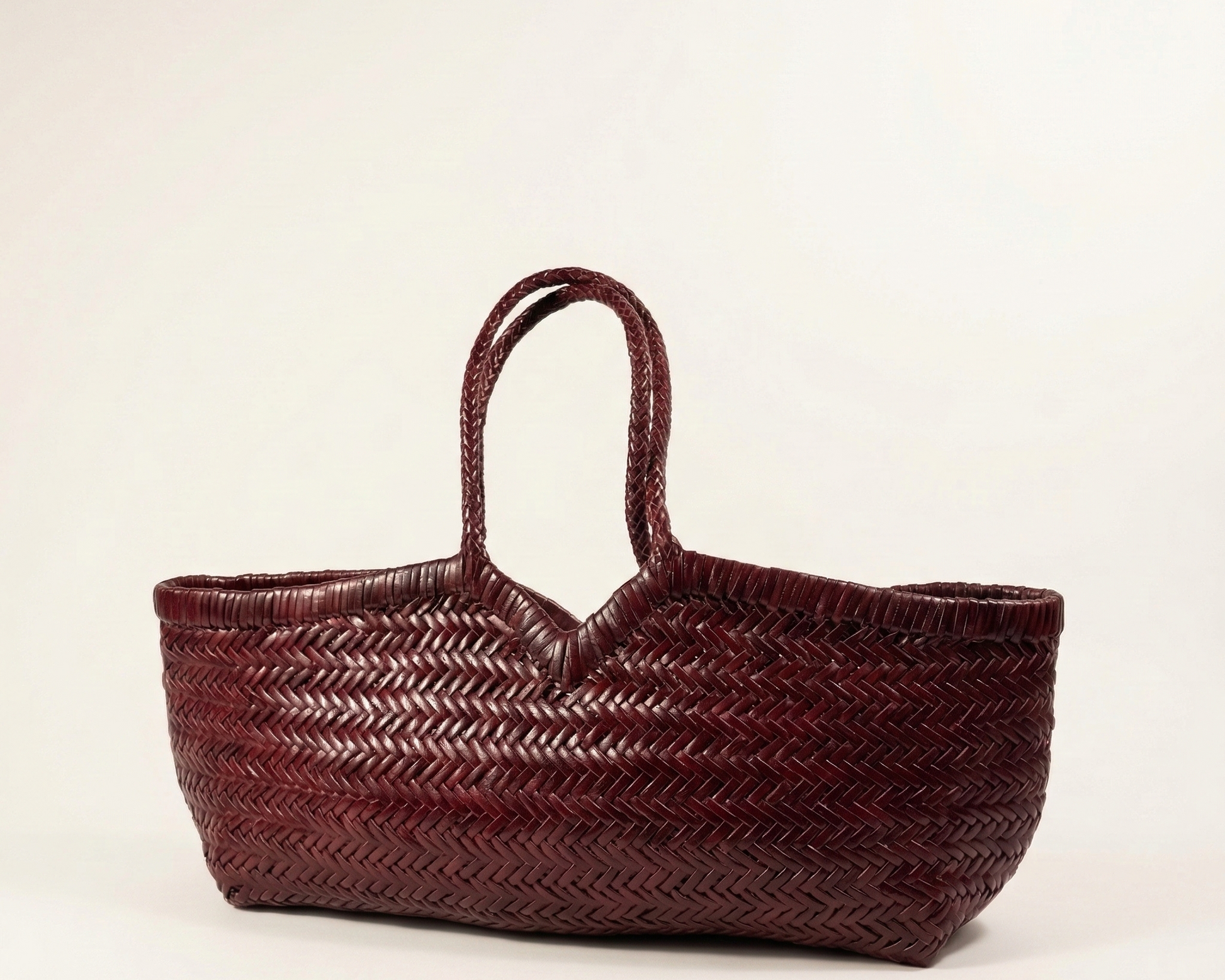 Angled view of the KAPSA woven leather shoulder bag in deep maroon
