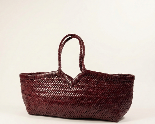 Woven maroon bag on a off white background