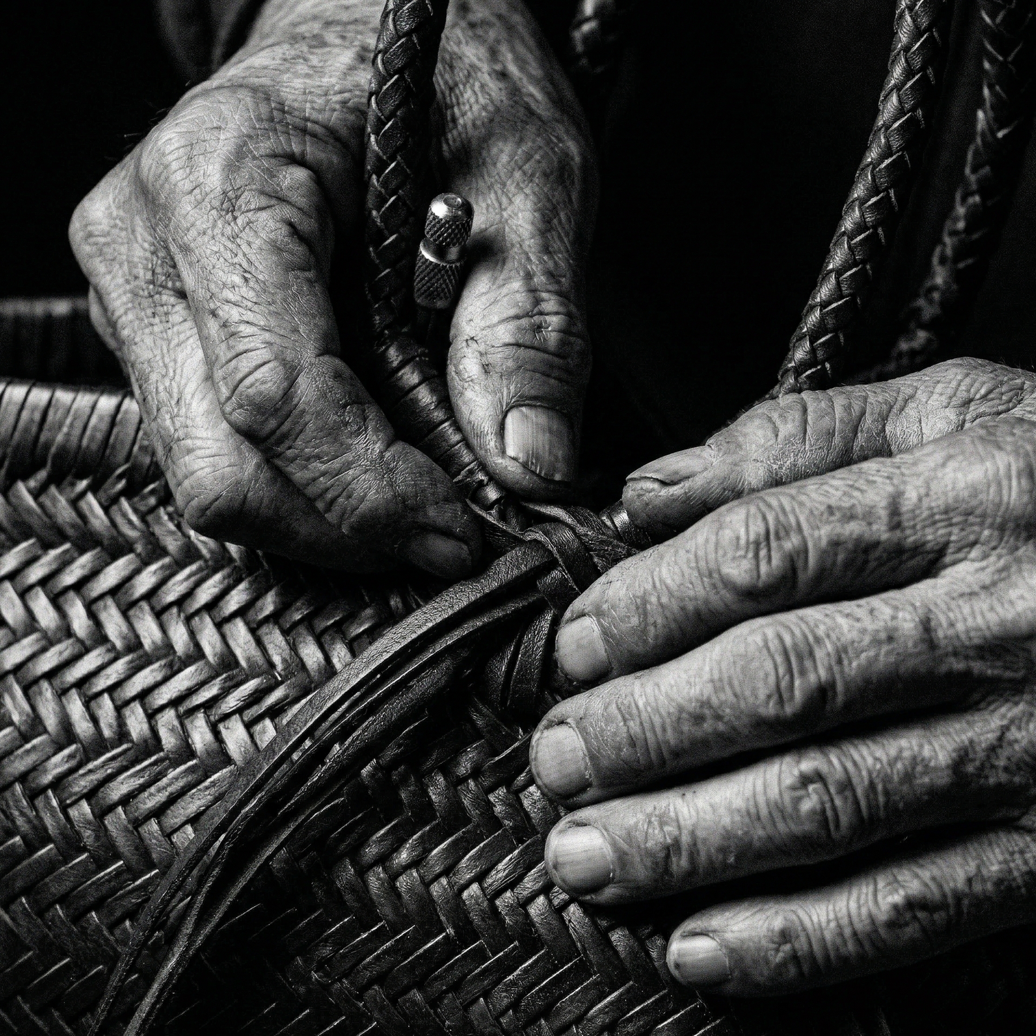 Close-up of hands working on a woven bag