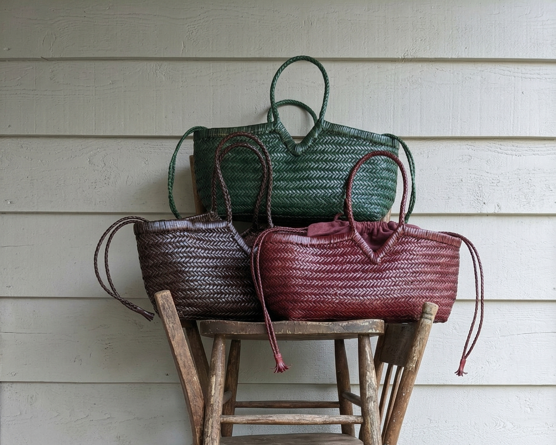Three woven bags on a stack of wooden stools against a light-colored wall.